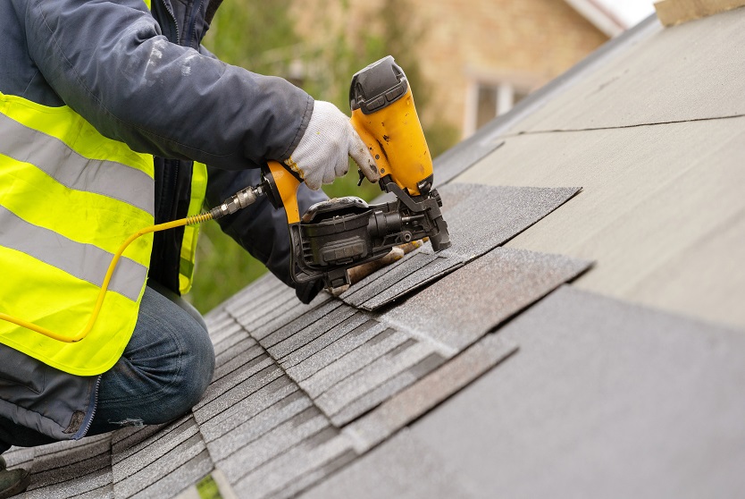 Roofing specialist installing asphalt shingles with nail gun in Melbourne